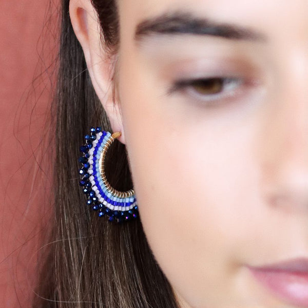 Elevate your style with our Beaded Fan Hoop Earrings in Blue! These golden hoop earrings feature a stunning blue mix striped multi bead fan detail that will add a touch of elegance and playfulness to any outfit. Make a statement and turn heads with these unique and eye-catching earrings.
