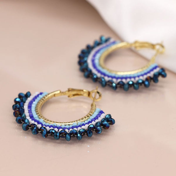 Elevate your style with our Beaded Fan Hoop Earrings in Blue! These golden hoop earrings feature a stunning blue mix striped multi bead fan detail that will add a touch of elegance and playfulness to any outfit. Make a statement and turn heads with these unique and eye-catching earrings.