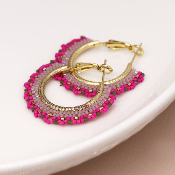 Elevate your style with our Beaded Fan Hoop Earrings in Pink! These golden hoop earrings feature a stunning pink mix striped multi bead fan detail that will add a touch of elegance and playfulness to any outfit. Make a statement and turn heads with these unique and eye-catching earrings.
