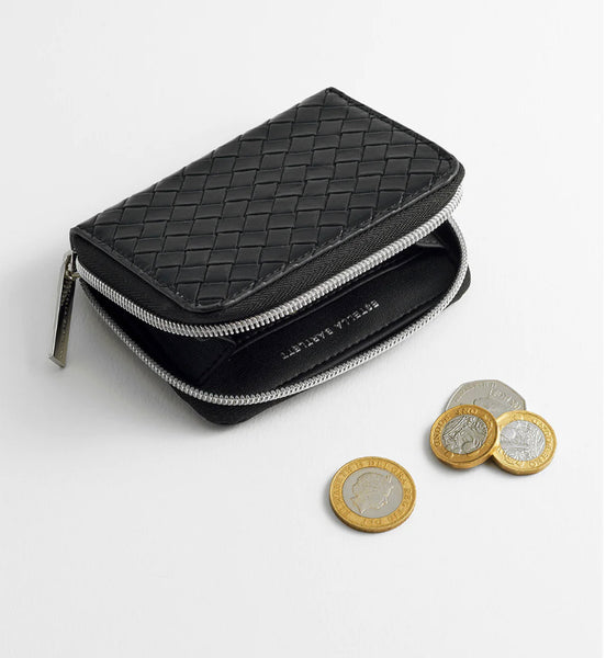 <p><br></p> This faux leather card purse in black features a woven design and a soft texture. Its multiple compartments offer convenient storage for cards and coins, giving you easy access and added confidence. It also includes silver hardware for a sleek and stylish touch.