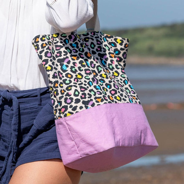 This lined cotton beach bag is perfect for a day at the beach. With a funky neon multicolour and black animal print, it adds a touch of fun to your beach essentials. The bag also features a lilac base and natural handles for easy carrying.