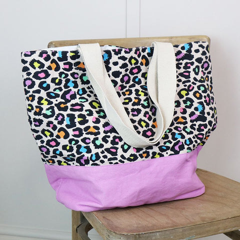 This lined cotton beach bag is perfect for a day at the beach. With a funky neon multicolour and black animal print, it adds a touch of fun to your beach essentials. The bag also features a lilac base and natural handles for easy carrying.