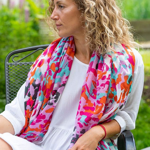 Made from soft, organic cotton, this scarf features a unique scattered animal print in striking shades of pink, red, and aqua. Perfect for adding a pop of color to any outfit, while staying environmentally conscious.  .Approximate size 100cm x 180cm  100% Organic cotton