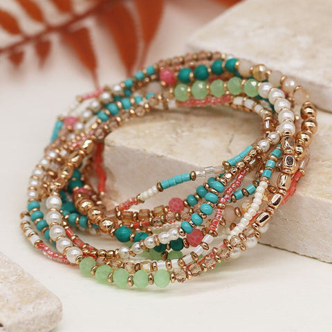 Indulge in this Multistrand Beaded Bracelet, featuring a mix of turquoise, coral, and rose gold beads with delicate pearls. The stretchy design effortlessly adds a touch of elegance to any outfit. Embrace a chic and stylish look with this must-have accessory.